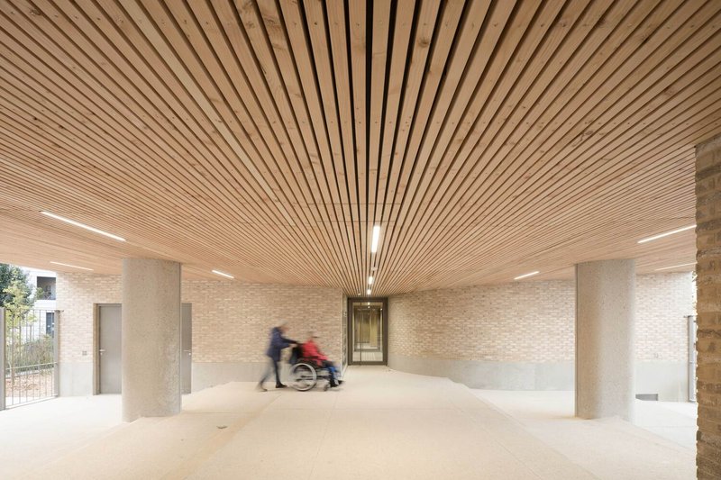 Ground floor entrance lobby with radiating timber slat ceiling and two figures moving through