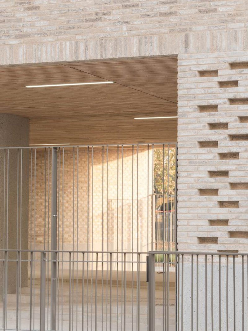 Floating timber staircase ascending alongside a pale brick wall with vertical metal railings below