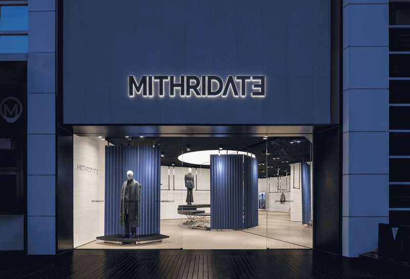 Storefront entrance with illuminated signage and blue composite panel facade at dusk