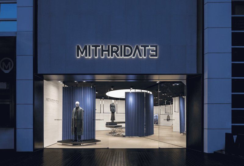 Storefront entrance with illuminated signage and full-height glazing at dusk