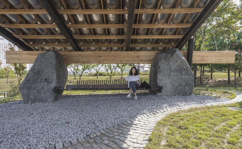 Bench seating between two rough-cut stone supports under the timber and tile roof canopy