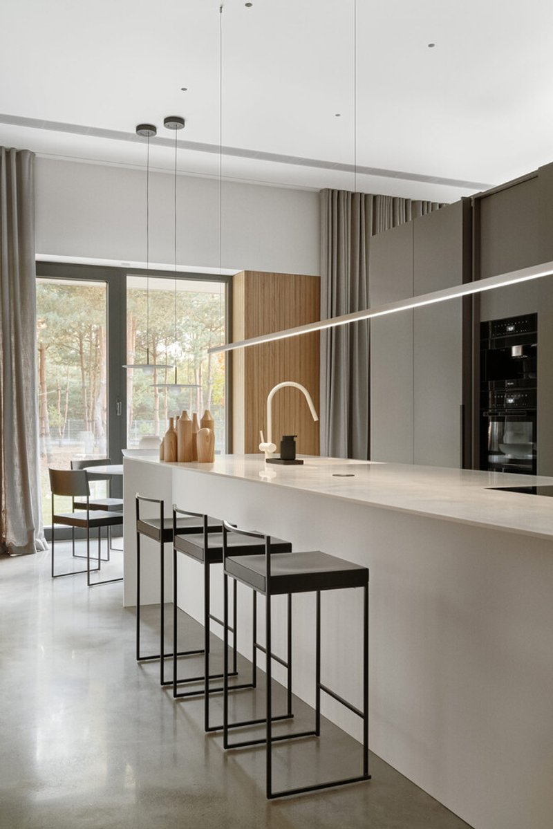 White kitchen island with bar stools and linear pendant light beneath a recessed ceiling slot