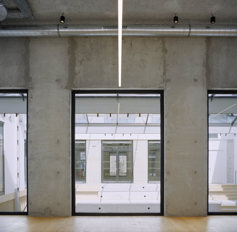 Interior window framing a view through the courtyard to the opposite building facade under diffused daylight
