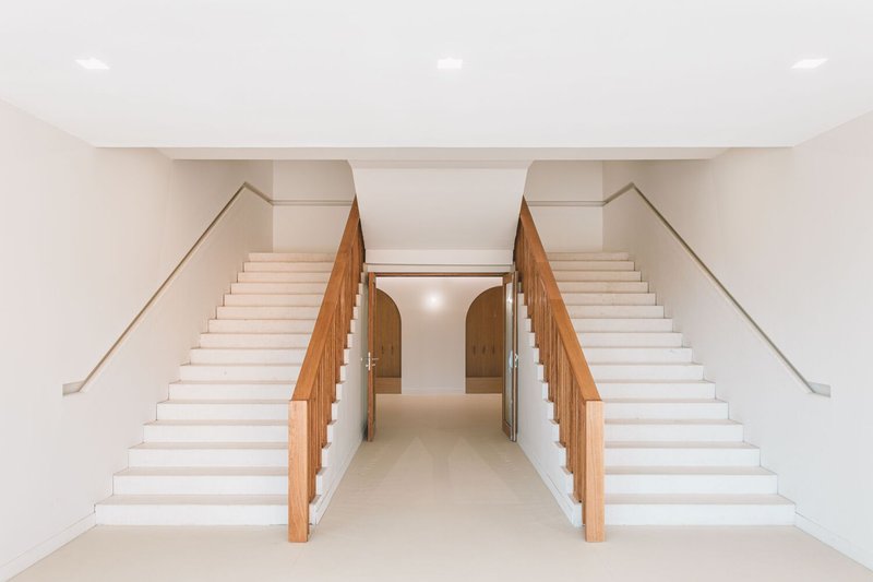 Symmetrical pair of staircases with timber balustrades converging on a central corridor below