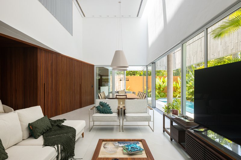 Living room with slatted timber wall and full-height glazing opening to the planted courtyard pool