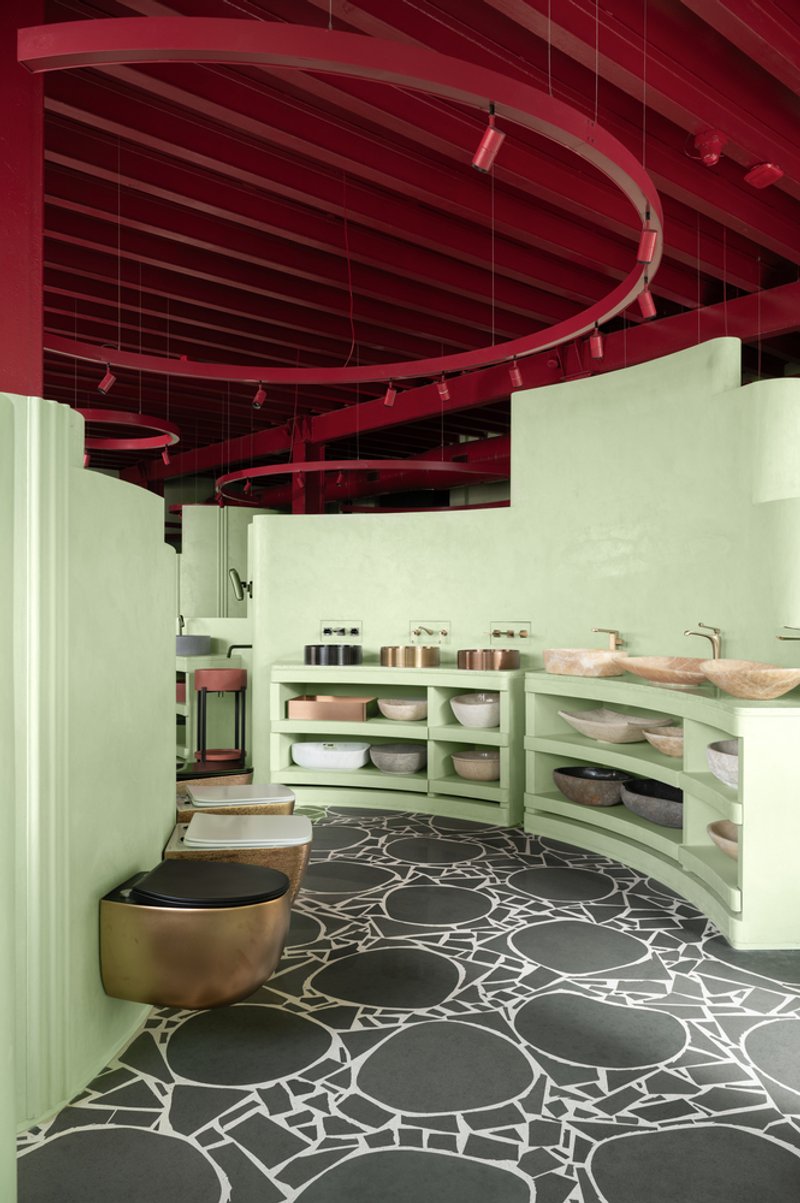 Curved vanity counter with open shelving displaying ceramic bowls and vessels below red metal ceiling structure