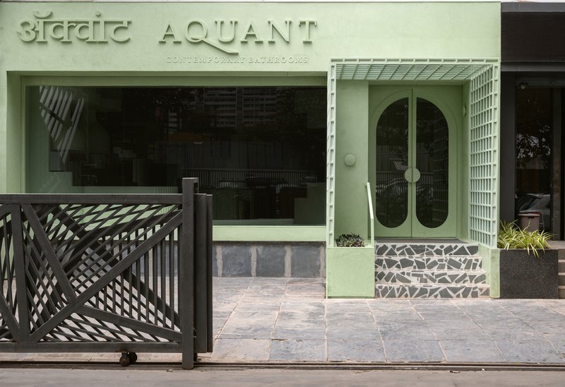 Street facade with pale green painted door and lattice screen gate beside bilingual signage in daylight