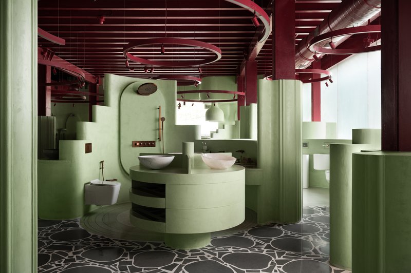 View across curved vanity with basin sinks toward pale green partitions under red painted ceiling with spiral ductwork