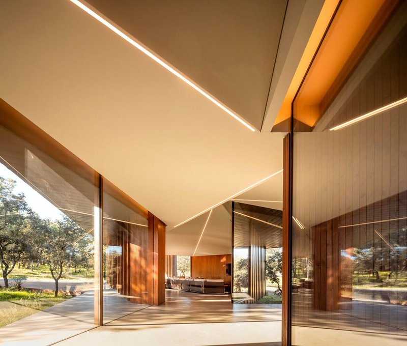 Open glazed corner with sliding timber doors and linear ceiling lighting beneath the angled roof plane