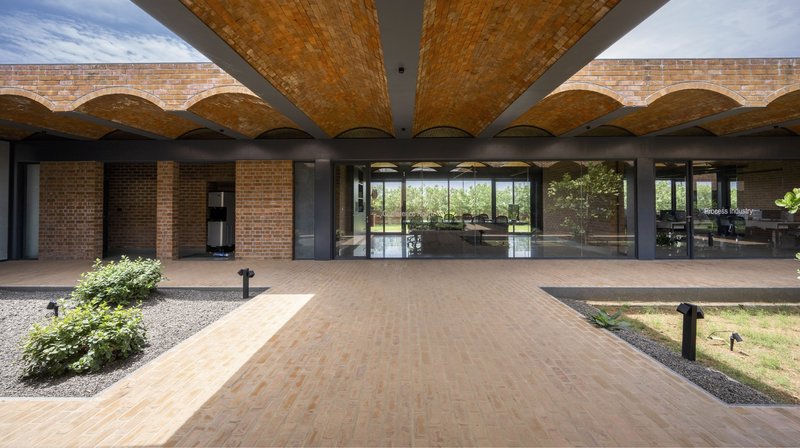 Symmetrical view along brick-paved path beneath radiating vaulted canopy toward glazed interior