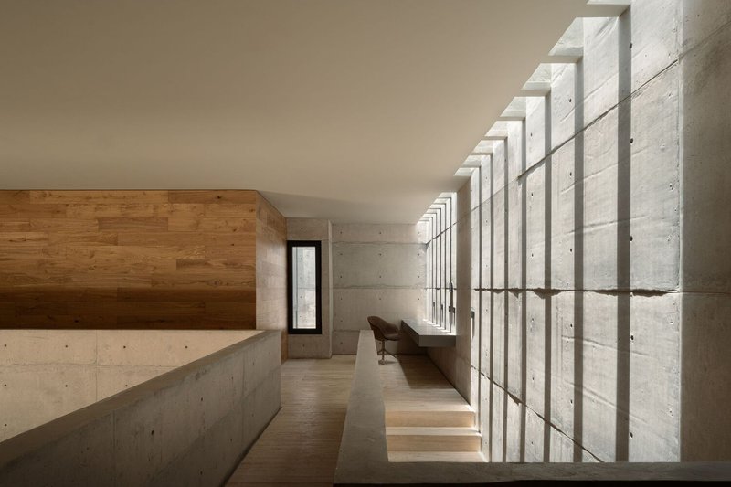 Upper-level corridor with rhythmic concrete fins creating vertical shadow patterns along the glass wall