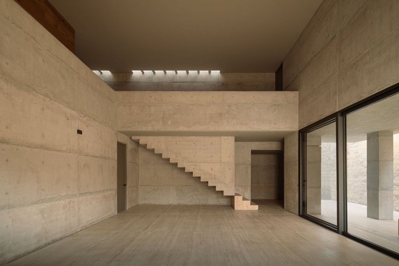 Double-height interior space with floating concrete staircase and timber-lined clerestory above