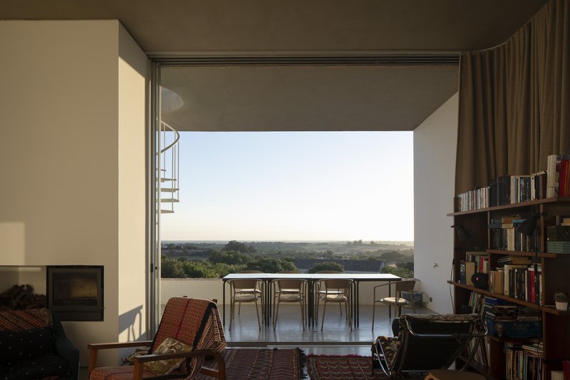 Open terrace with dining table framing a panoramic view across the valley at sunset
