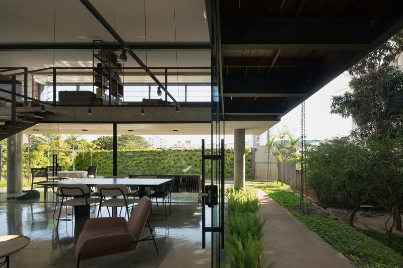Interior dining area with mezzanine above opening onto landscaped pathway beside glass facade