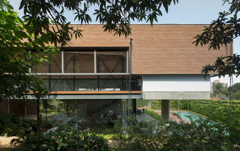Elevated volume clad in horizontal wood slats with glazed lower level and framed by overhanging tree branches