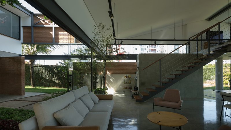 Double-height living space with concrete stair and ceiling framing views to planted courtyard beyond