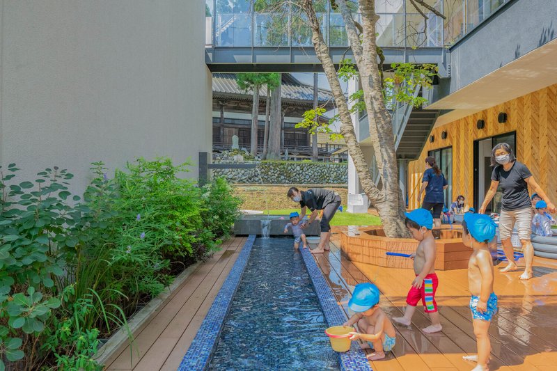 Courtyard with a blue-tiled water channel bordered by timber decking and children gathered around it