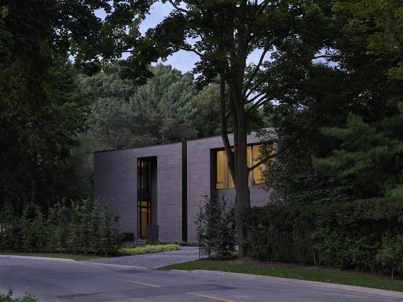 Brick residence set among mature trees along a residential street at twilight