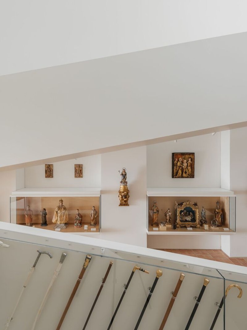 White display cases with religious artifacts arranged along an angled gallery wall