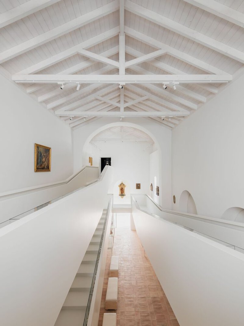 Interior view of the vaulted gallery space with exposed timber trusses and terra cotta tile floor below