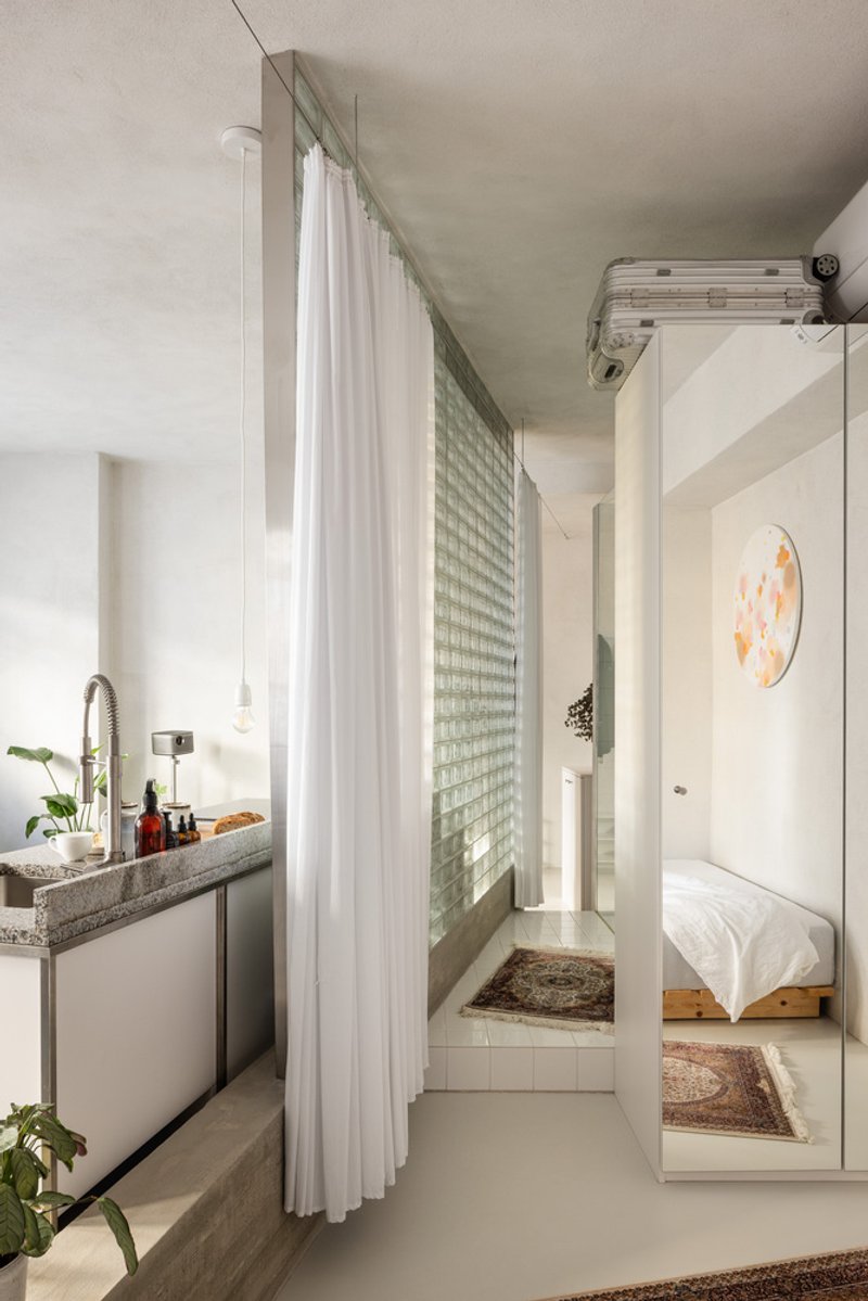 View toward bedroom with glass block window wall behind sheer white curtain and mirrored wardrobe