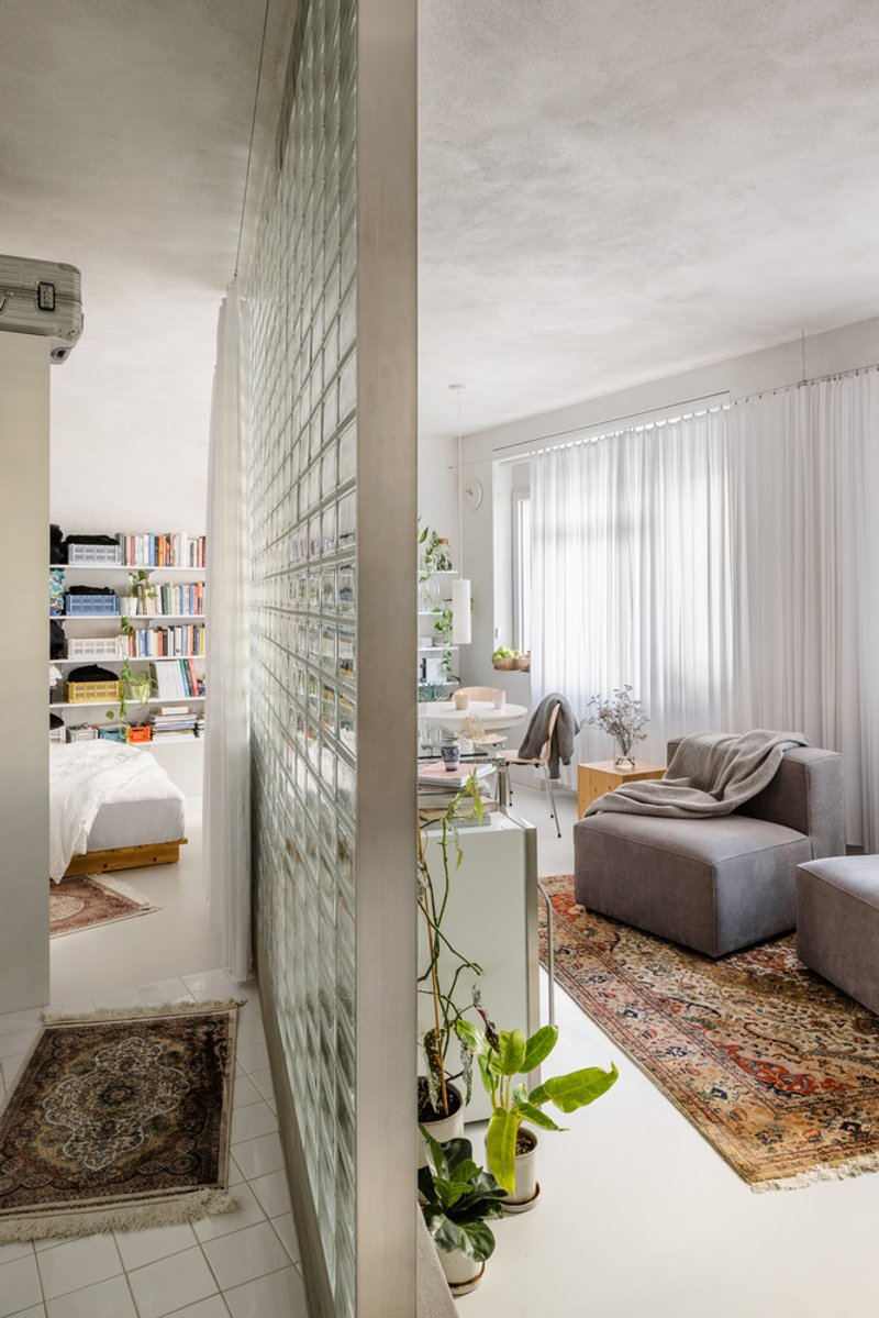 Translucent glass block wall separating the living room from the bedroom with potted plants at its base