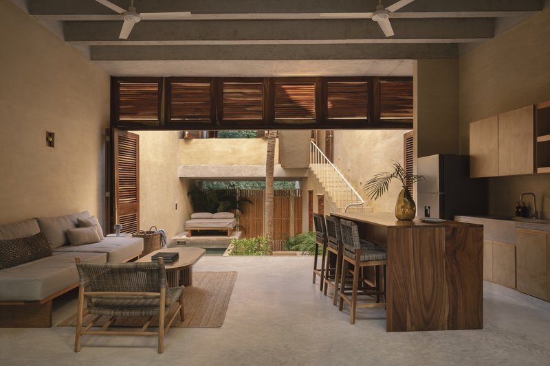 Open-plan living space with walnut kitchen island and slatted timber doors framing courtyard view