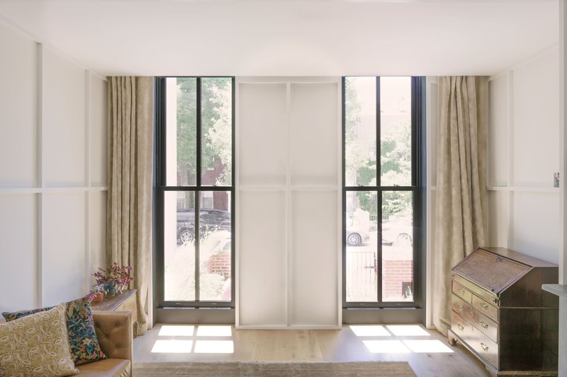 Interior room with tall black-framed windows flanking a central white closet under bright daylight
