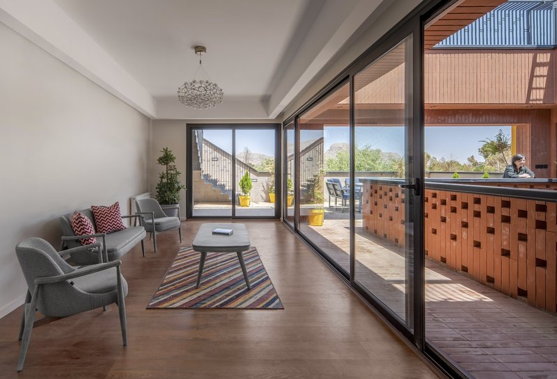 Interior living room opening through sliding glass doors to a terrace with chequered brick screening under bright daylight