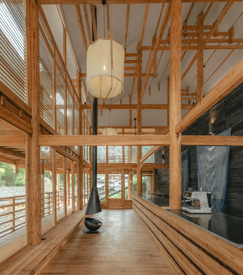 Double-height interior with exposed timber framing and a pendant lantern above a fireplace