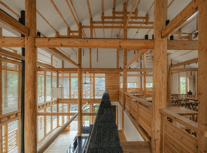Interior view through timber post-and-beam structure with kitchen and dining areas beyond