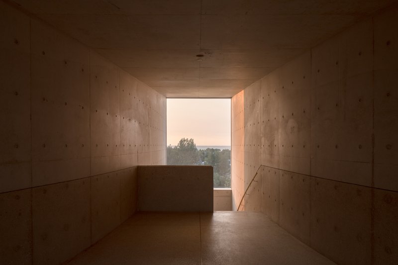 Concrete corridor framing distant landscape view through opening at dusk