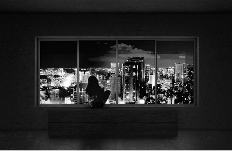 Panoramic window framing the illuminated cityscape at night with a solitary figure in silhouette
