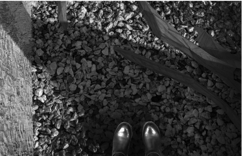 Overhead view of gravel ground surface with timber edging and the photographer's boots visible