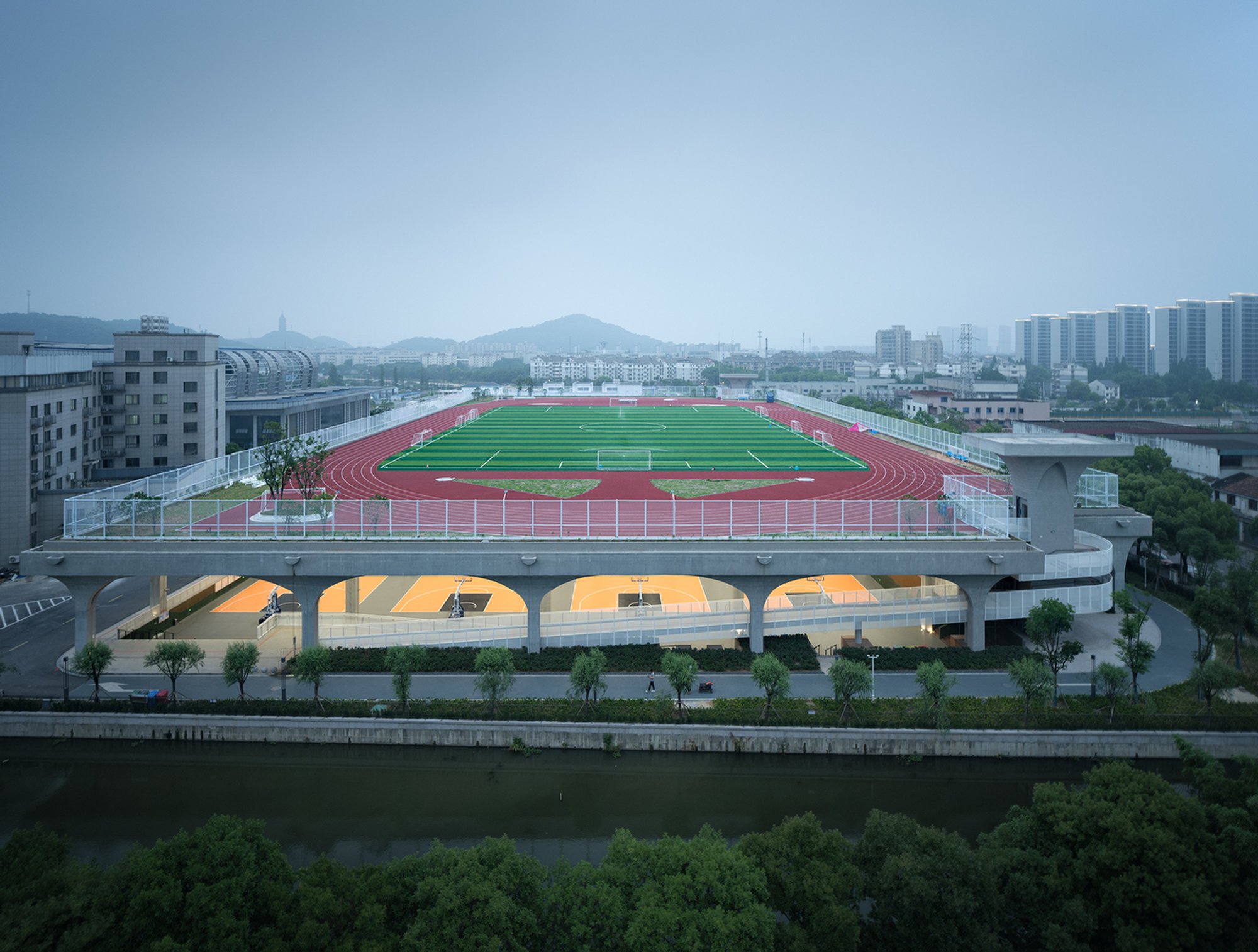UAD Lifts a Football Pitch into the Sky to Shelter an Entire Sports Complex Beneath It