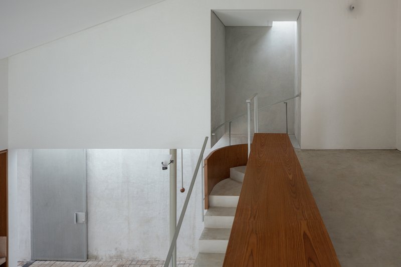 Upper level landing with glass guardrail and timber-clad volume overlooking the floor below
