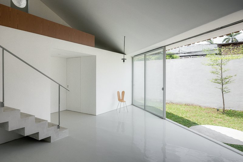Interior living space with polished floor, open staircase and full-height glazing to the garden