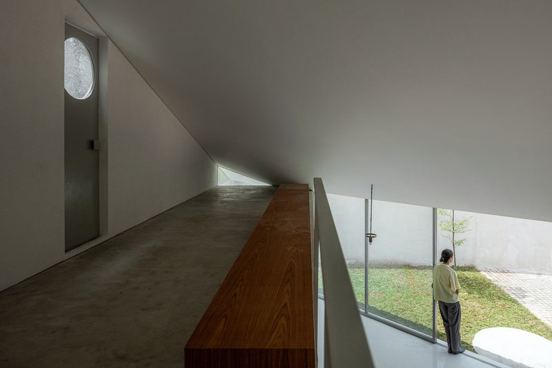 Upper corridor with timber volume and person standing at the window overlooking the courtyard