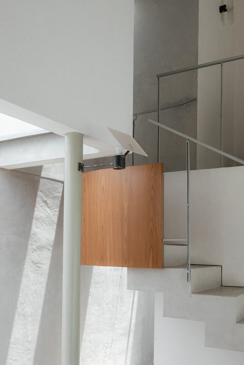 Stairwell detail showing timber cabinetry, glass railing and a cylindrical column under skylight