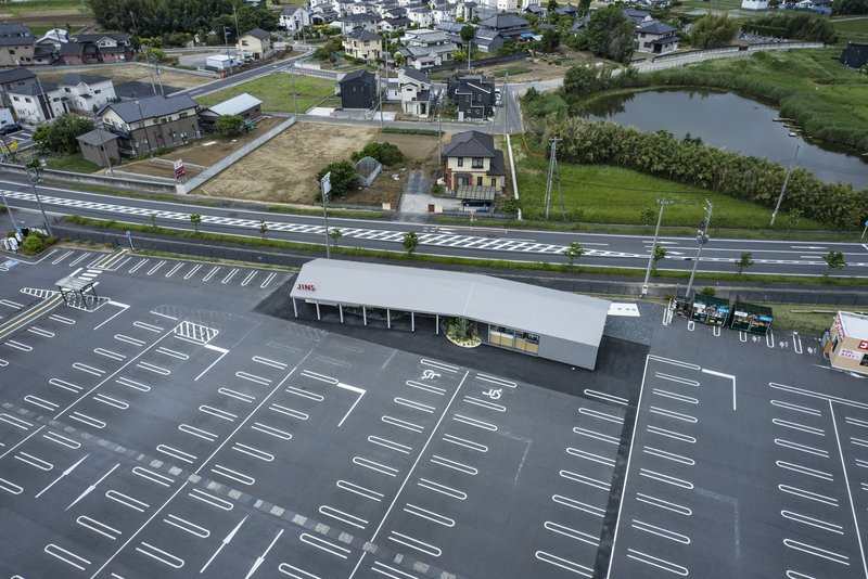 Aerial view of the single-story pavilion with white roof in a parking lot beside residential houses