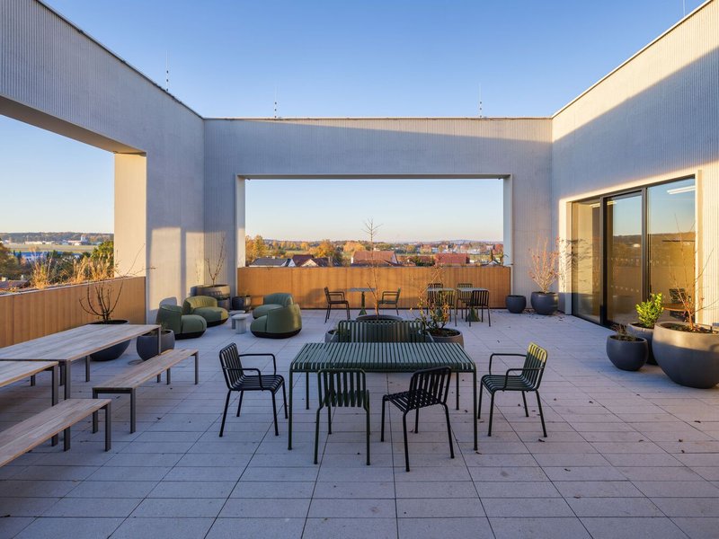 Rooftop terrace with outdoor furniture and framed view of distant landscape at sunset