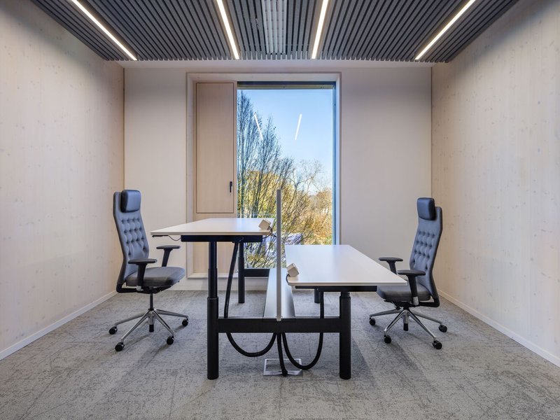 Meeting room with two desks and office chairs facing a window opening to bare winter trees