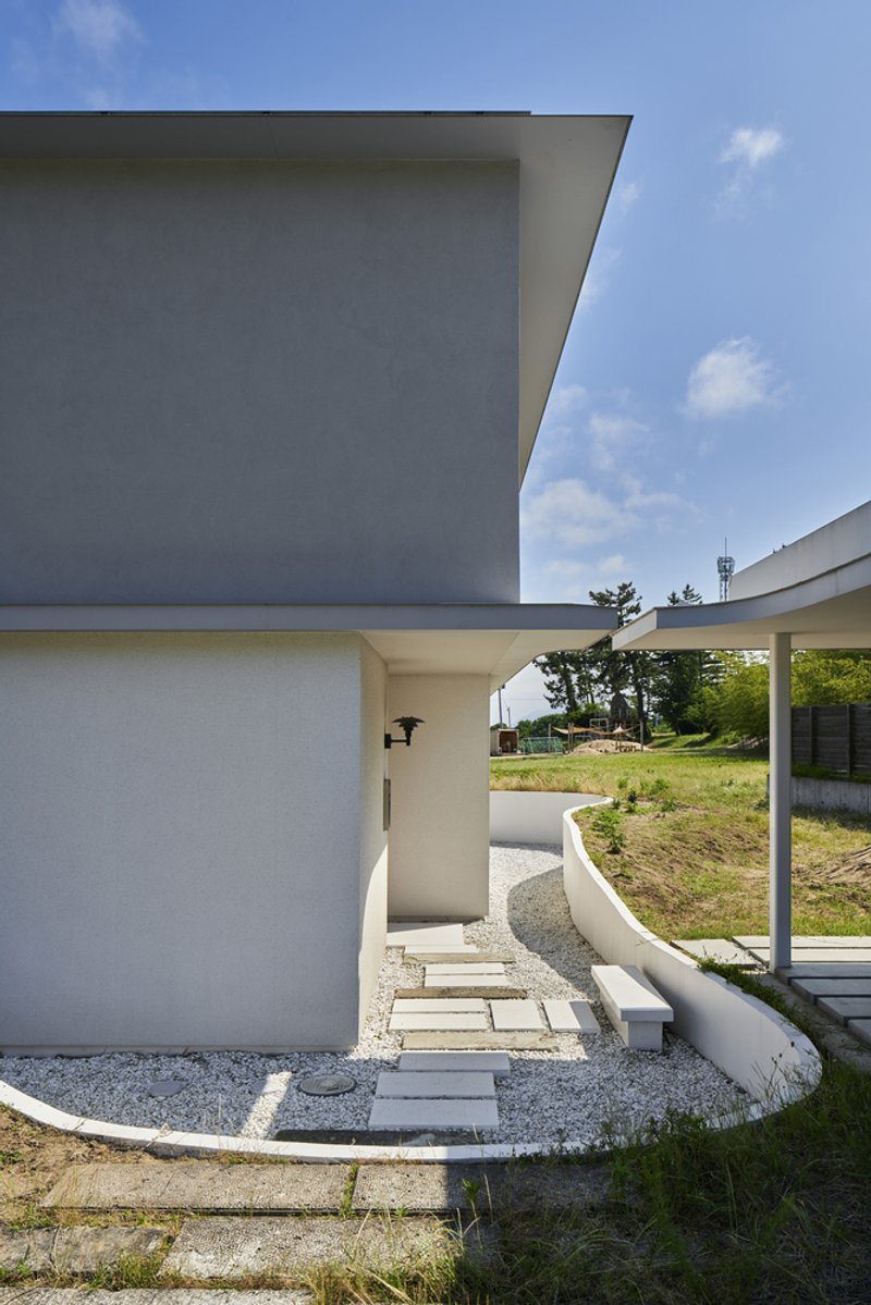 Entry pathway with stepping stones through gravel leading to recessed doorway beneath carport