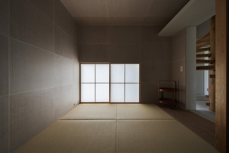 Tatami room with grey textile-clad walls and translucent shoji screens diffusing soft daylight