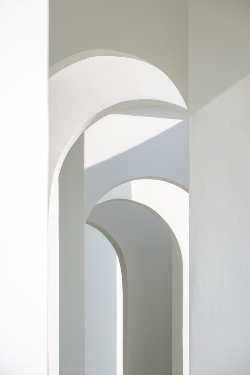 Interior view of layered arched openings in white plaster with natural light filtering through