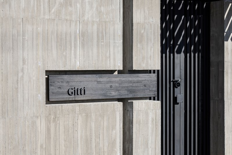 Painted timber mailbox attached to a vertical slatted screen beside a pale timber wall
