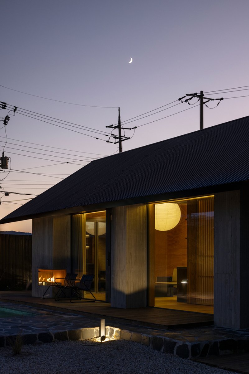 Glazed porch with glowing interior light and crescent moon overhead at dusk