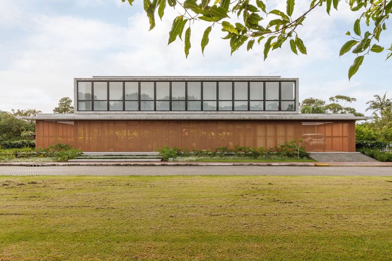 Street elevation showing the vertical timber facade below a glazed upper volume and expansive lawn