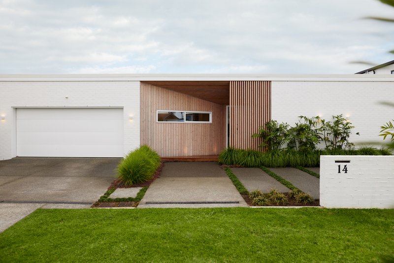 Entry driveway with concrete pavers in grass strips leading to timber-clad facade