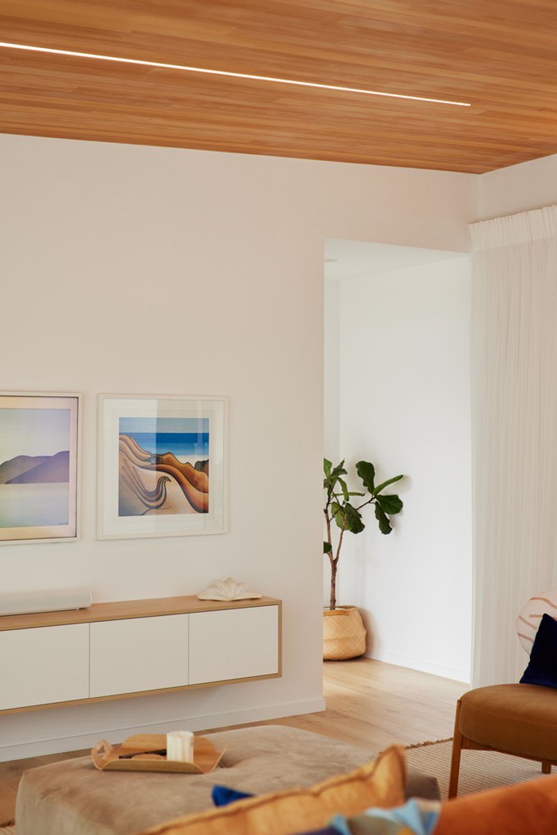 Interior corner with timber ceiling, wall-mounted credenza, potted plant and framed artworks on white walls